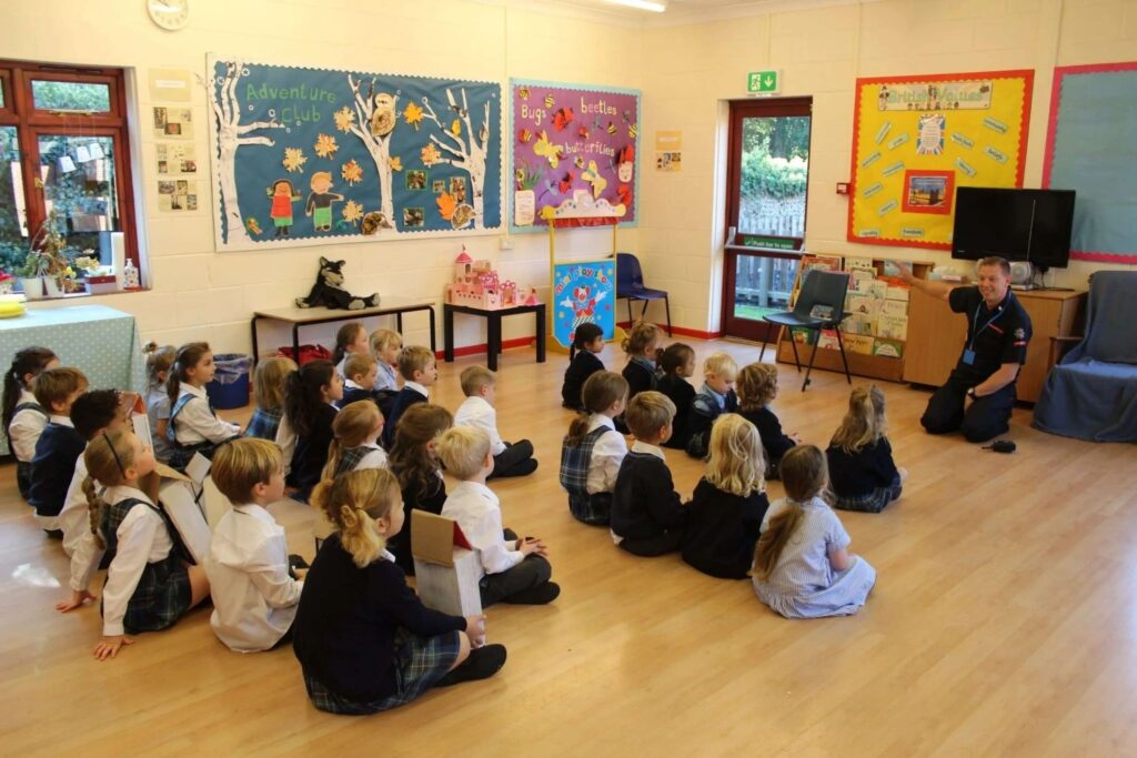 Pupils sitting together on the floor of a bright classroom