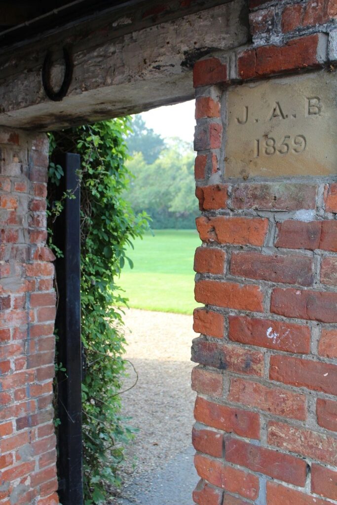 Brick archway with a carved datestone leading through to the lawns of the Old Hall